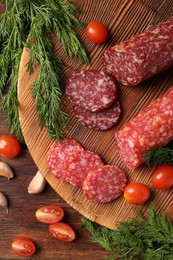 Photo of Different smoked sausages, cherry tomatoes and spices on wooden table, flat lay