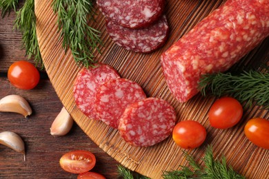 Photo of Different smoked sausages, cherry tomatoes and spices on wooden table, flat lay