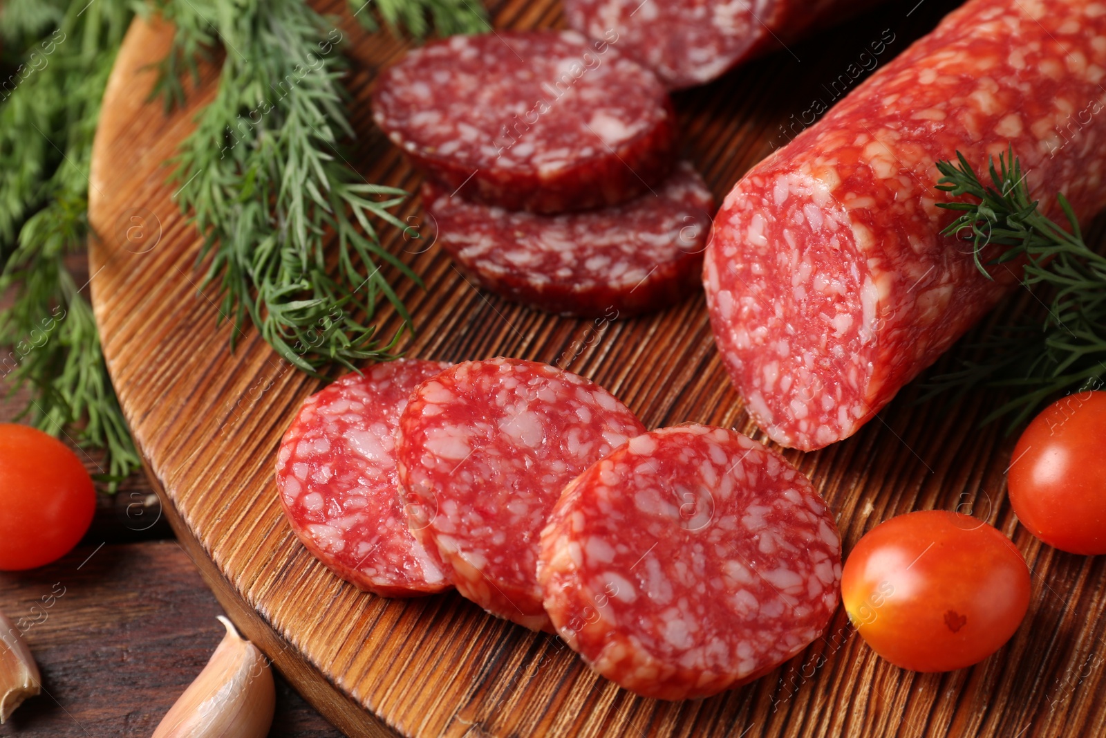 Photo of Different smoked sausages, cherry tomatoes and spices on wooden table, closeup