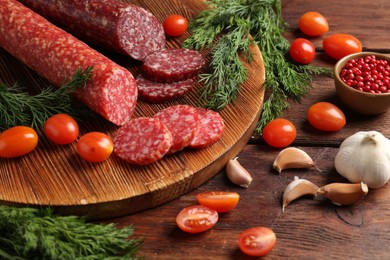 Photo of Different smoked sausages, cherry tomatoes and spices on wooden table, closeup