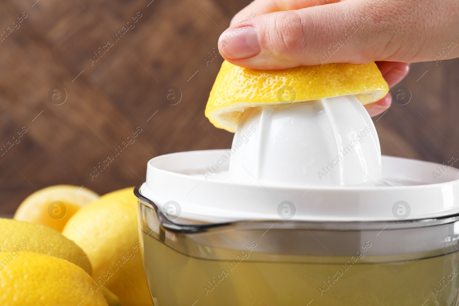 Photo of Woman with lemon using juicer at wooden table, closeup