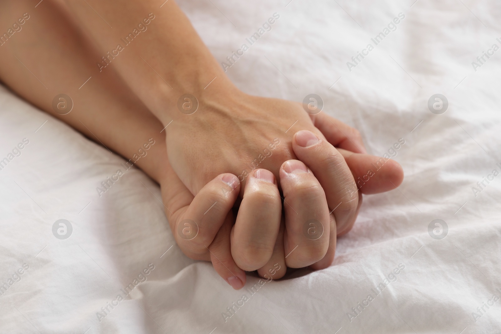 Photo of Lovely couple holding hands in bed, closeup