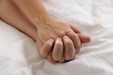 Photo of Lovely couple holding hands in bed, closeup