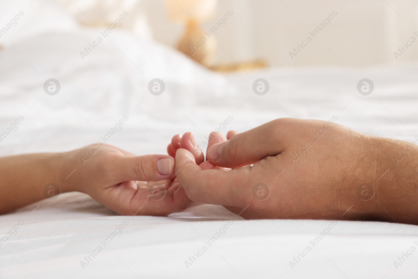 Photo of Lovely couple holding hands in bed, closeup