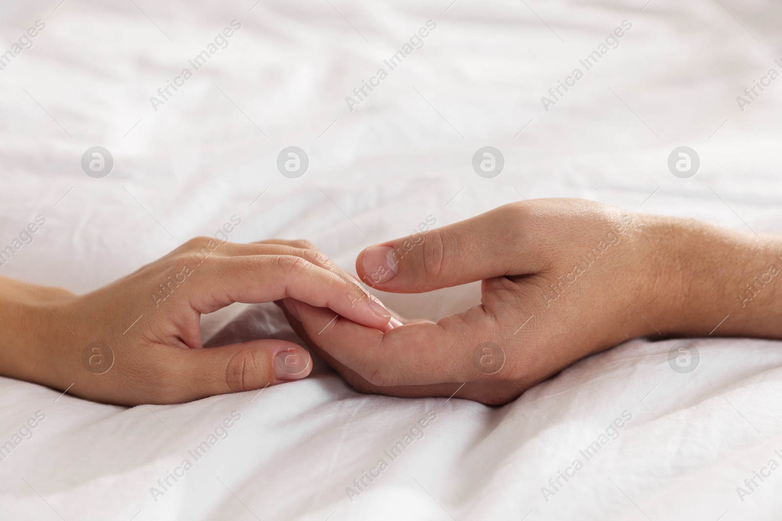 Photo of Lovely couple holding hands in bed, closeup