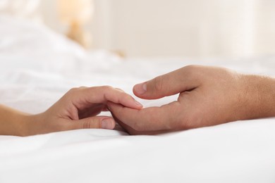 Photo of Lovely couple holding hands in bed, closeup