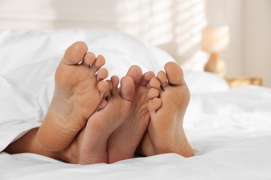 Photo of Couple lying in bed with white sheets, closeup