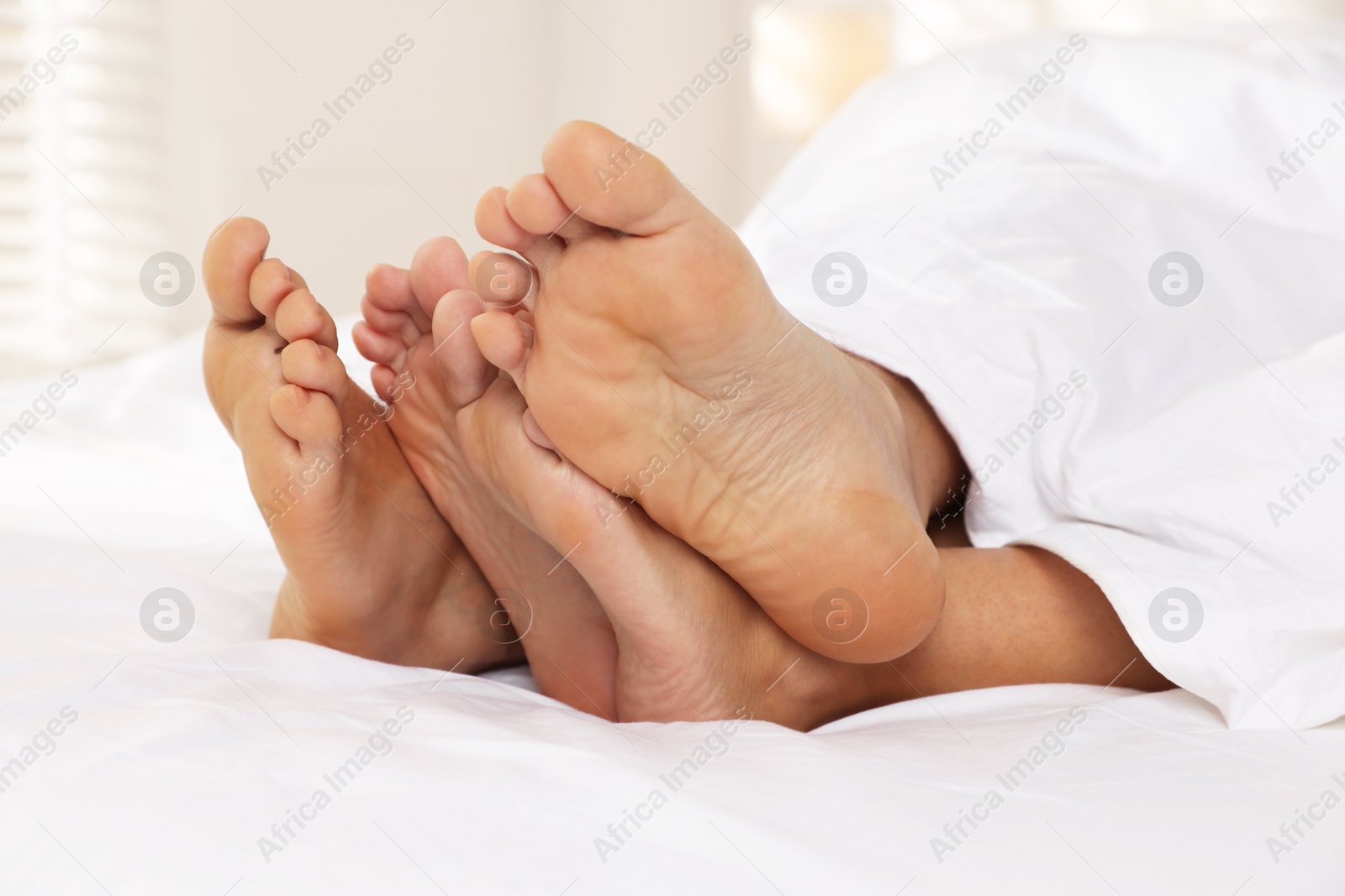 Photo of Couple lying in bed with white sheets, closeup