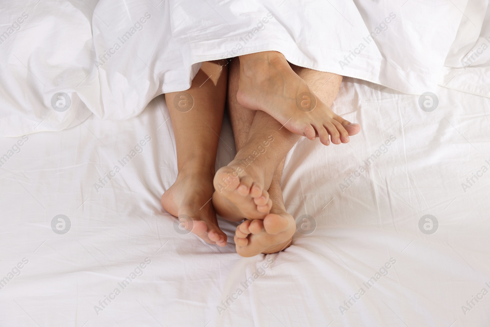 Photo of Couple lying in bed with white sheets, closeup