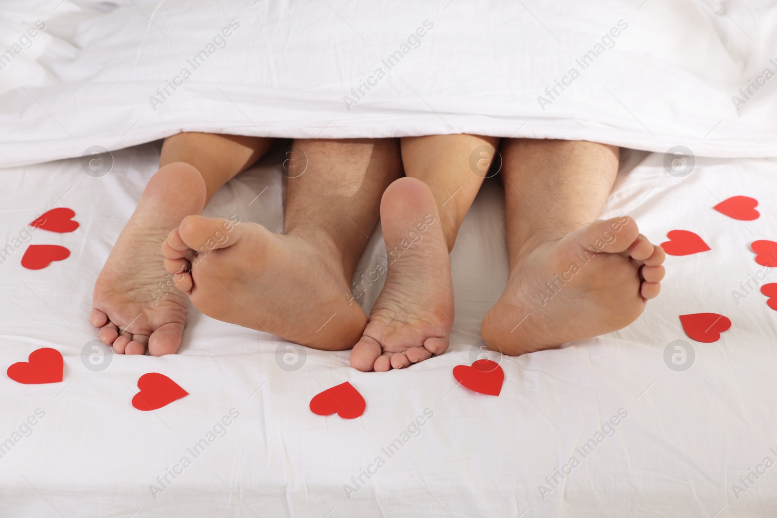 Photo of Couple lying in bed with red paper hearts, closeup