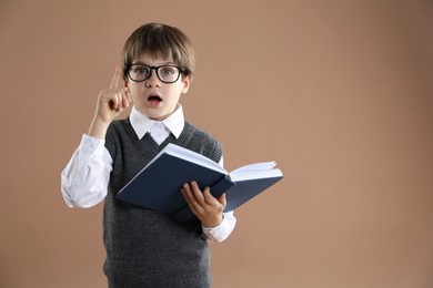 Photo of Learning alphabet. Little boy with book on brown background, space for text