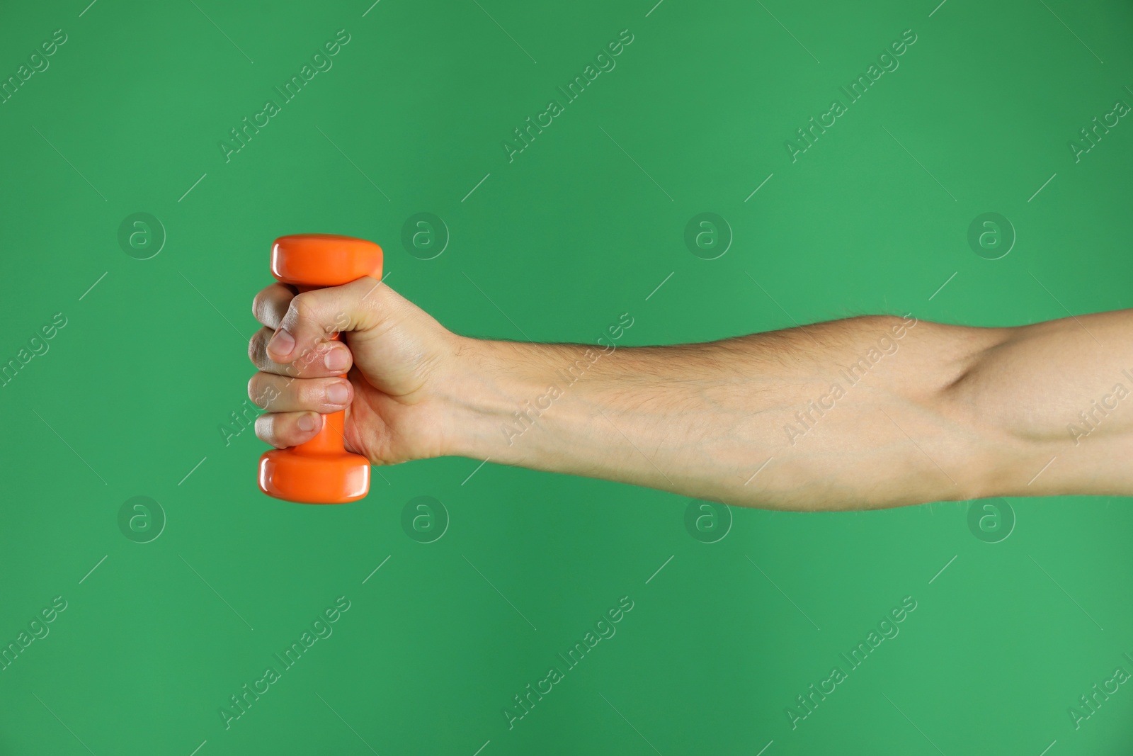 Photo of Man exercising with dumbbell on green background, closeup