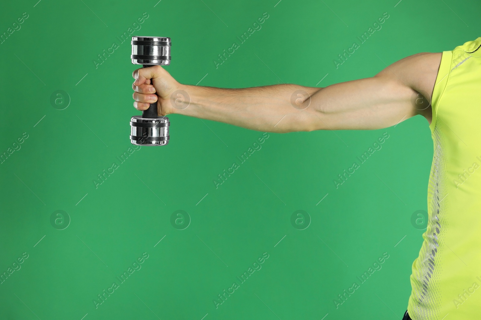 Photo of Man exercising with dumbbell on green background, closeup