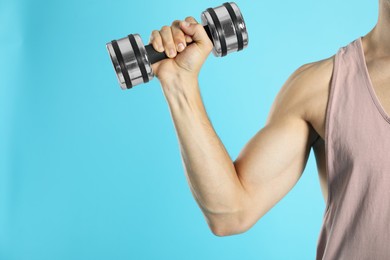 Photo of Man exercising with dumbbell on light blue background, closeup. Space for text