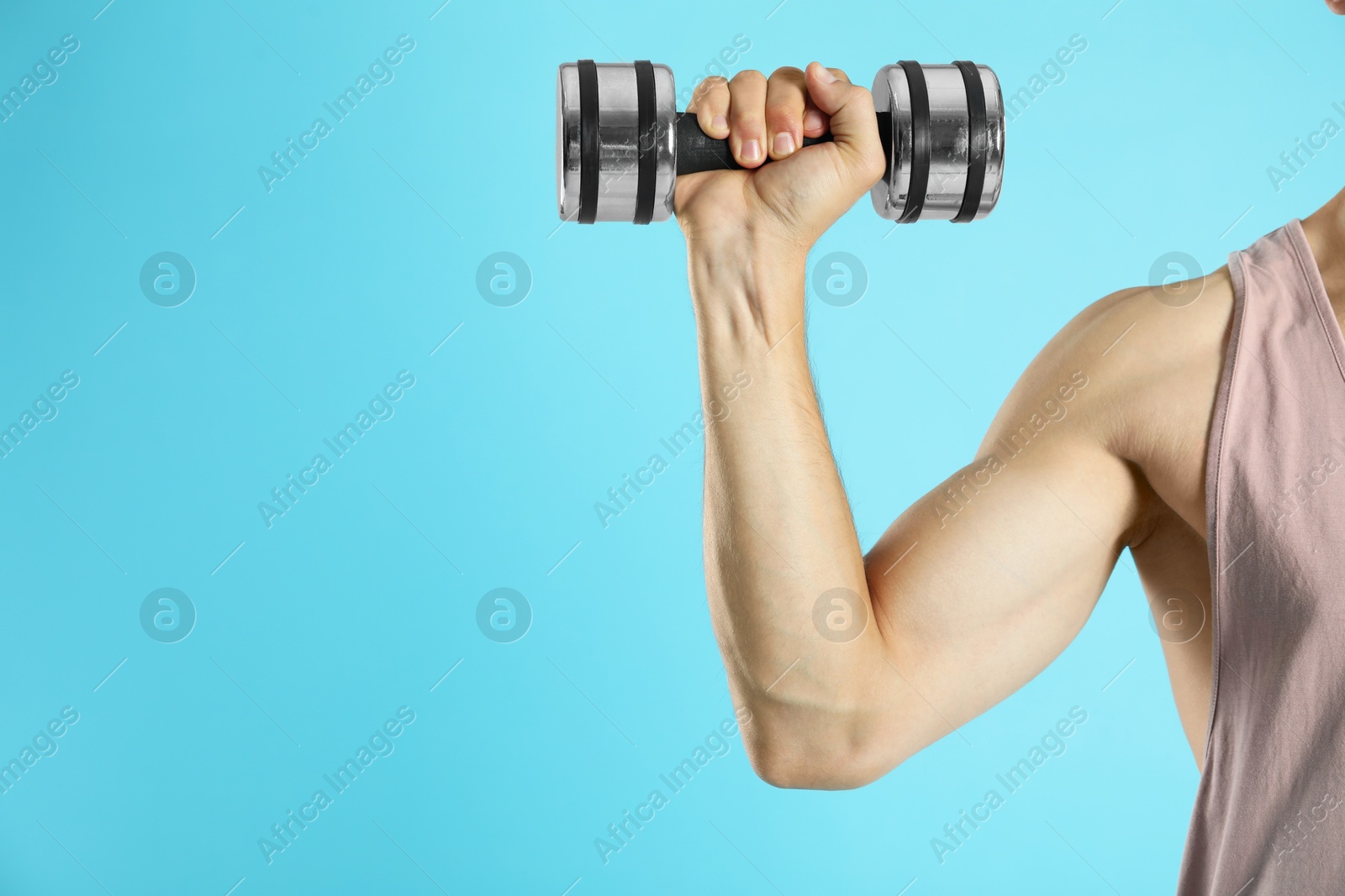 Photo of Man exercising with dumbbell on light blue background, closeup. Space for text