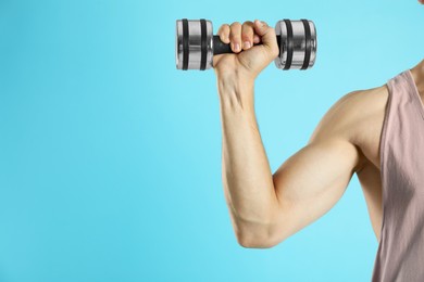 Photo of Man exercising with dumbbell on light blue background, closeup. Space for text