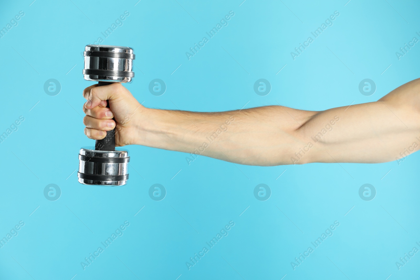 Photo of Man exercising with dumbbell on light blue background, closeup