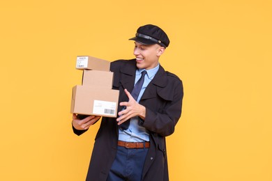 Photo of Happy postman with parcels on yellow background