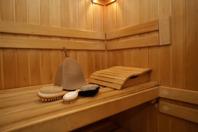 Photo of Felt wool hat and bath accessories on wooden bench in sauna