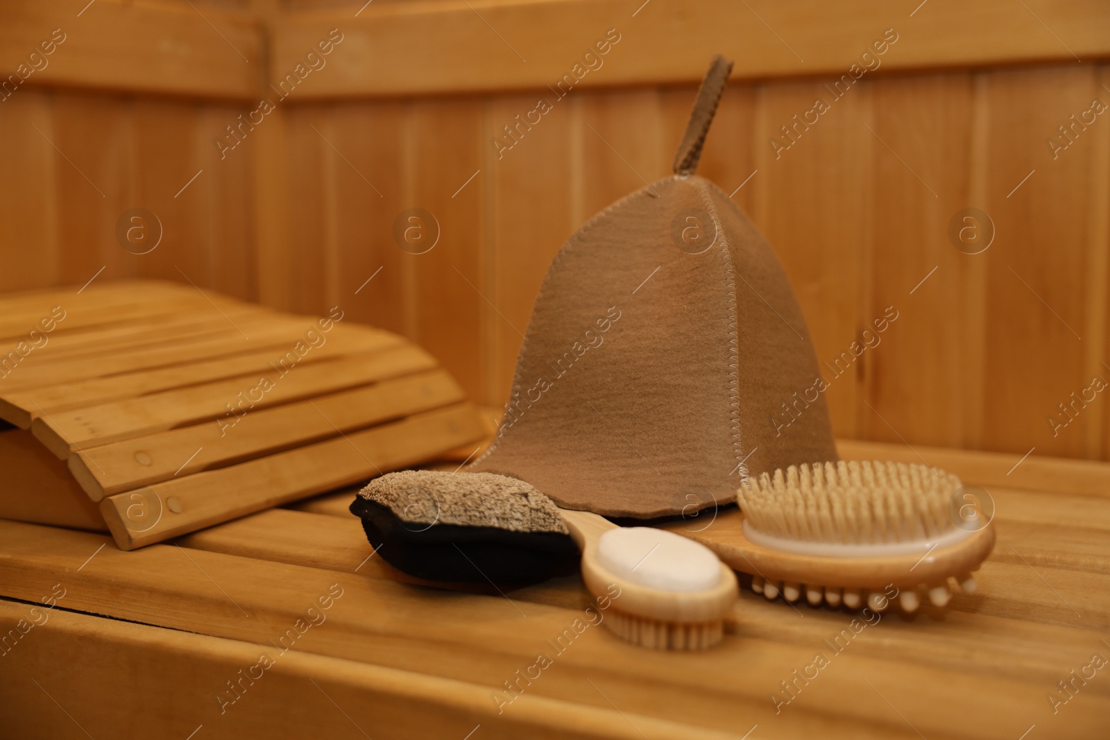 Photo of Felt wool hat and bath accessories on wooden bench in sauna