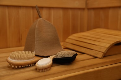 Photo of Felt wool hat and bath accessories on wooden bench in sauna