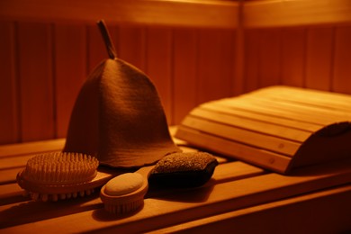 Photo of Felt wool hat and bath accessories on wooden bench in sauna