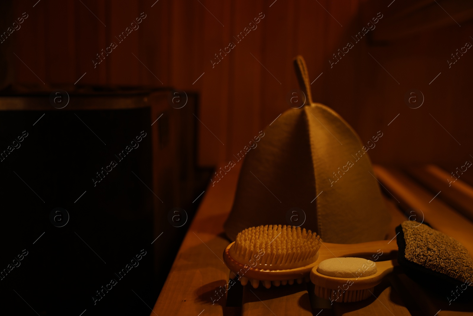 Photo of Bath accessories and felt wool hat on bench in sauna. Space for text