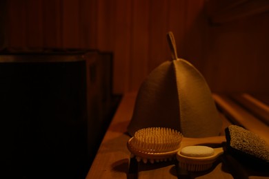 Photo of Bath accessories and felt wool hat on bench in sauna. Space for text