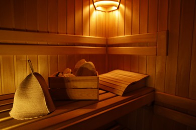 Photo of Crate with bath accessories and felt wool hat on bench in sauna. Space for text