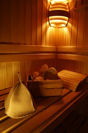 Photo of Crate with bath accessories and felt wool hat on bench in sauna