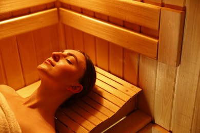 Photo of Beautiful woman relaxing on bench in sauna