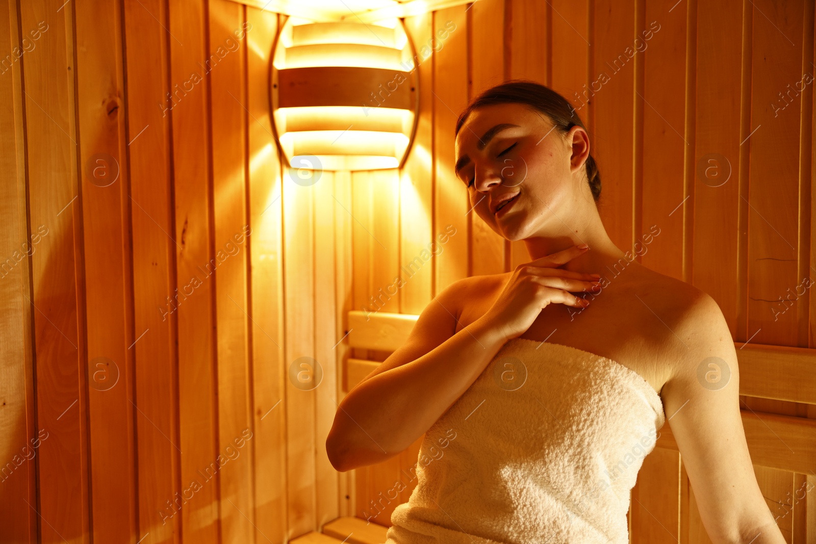 Photo of Beautiful woman wrapped in towel at sauna. Space for text