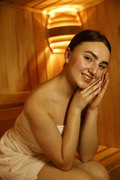 Photo of Beautiful woman wrapped in towel on bench at sauna