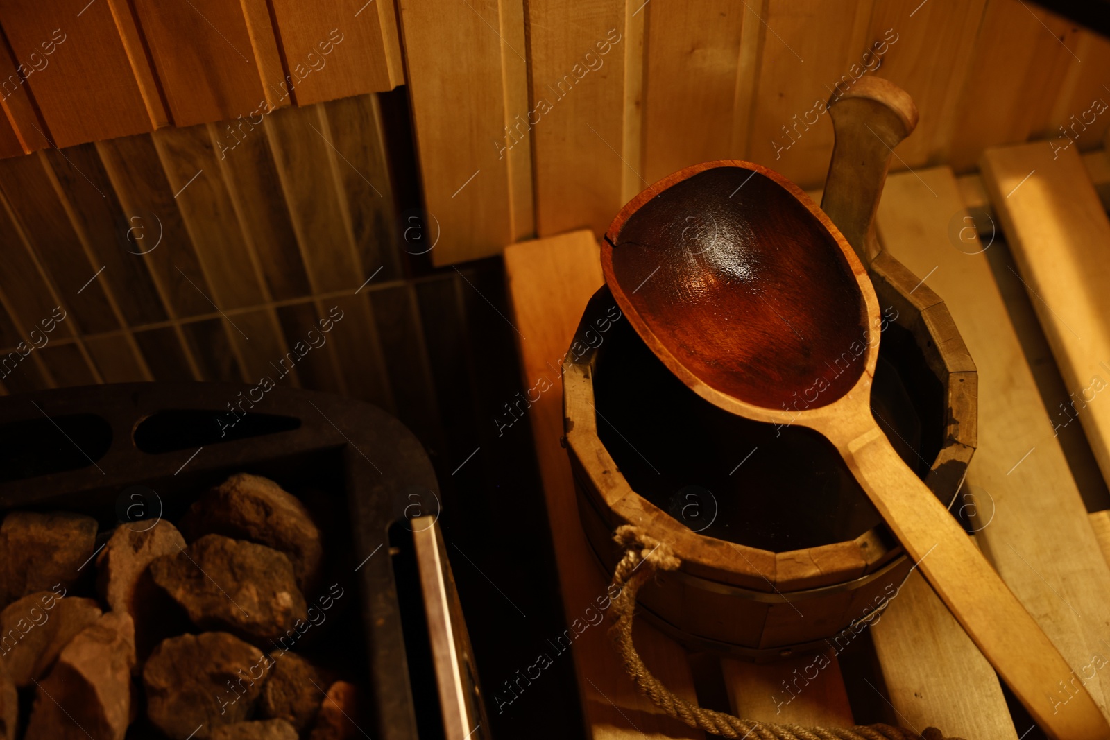 Photo of Bucket and ladle on wooden bench in sauna, closeup