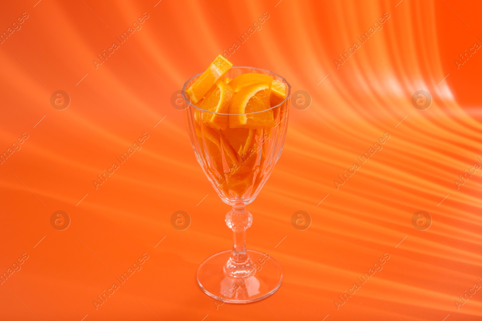 Photo of Orange slices in cocktail glass on orange background