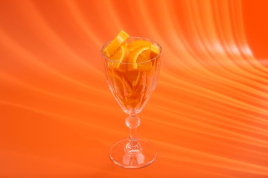 Photo of Orange slices in cocktail glass on orange background