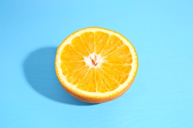 Photo of Half of orange on light blue background. Citrus fruit