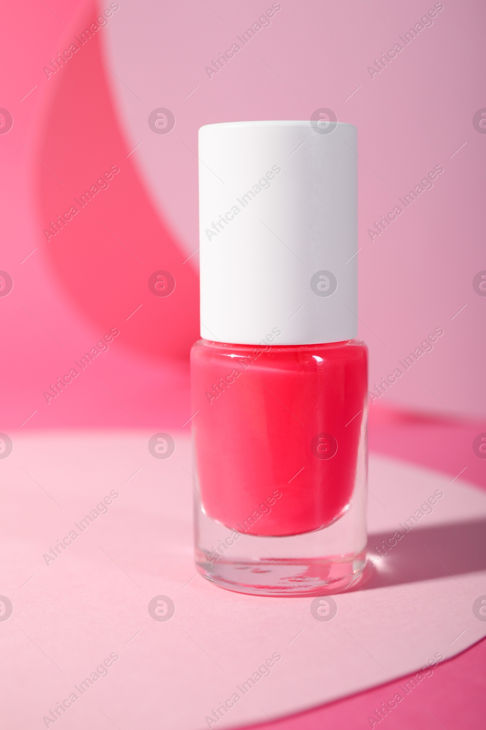 Photo of Nail polish in bottle on pink background