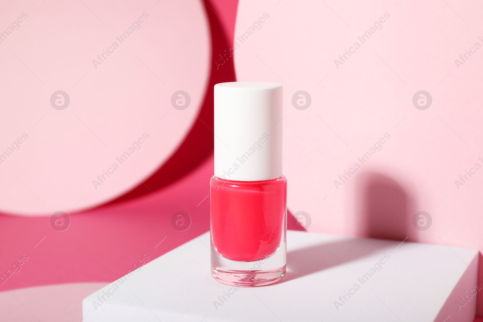 Photo of Stylish presentation of nail polish in bottle on pink background