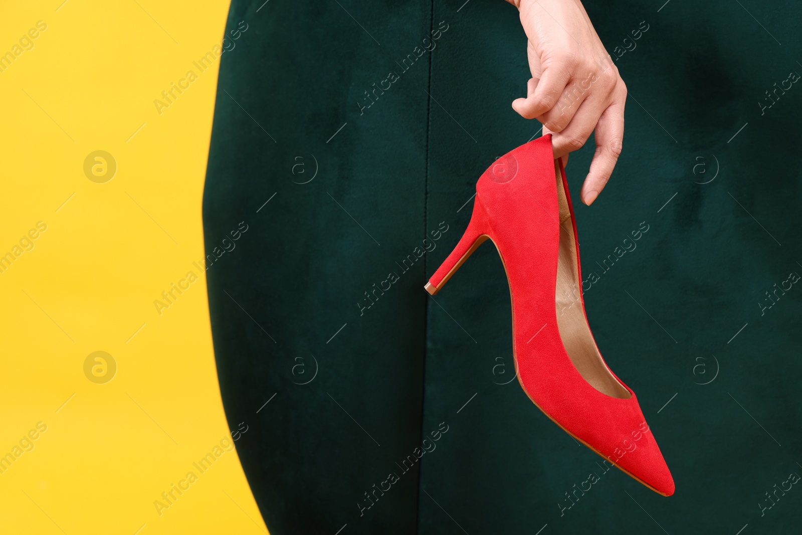 Photo of Woman holding red high-heeled shoe on color background, closeup