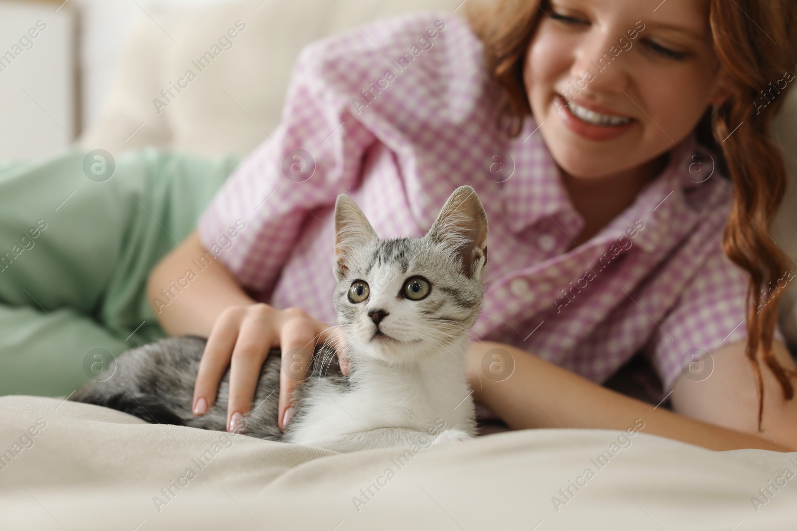 Photo of Teenage girl with cute cat on sofa at home, selective focus