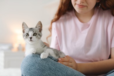 Photo of Teenage girl with cute cat indoors, closeup