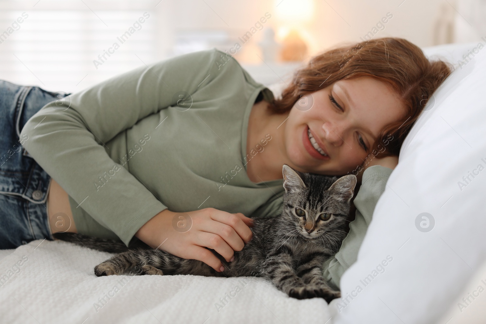 Photo of Beautiful teenage girl with cute cat on bed at home