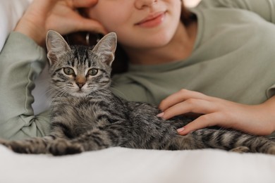 Photo of Teenage girl with cute cat on bed at home, closeup