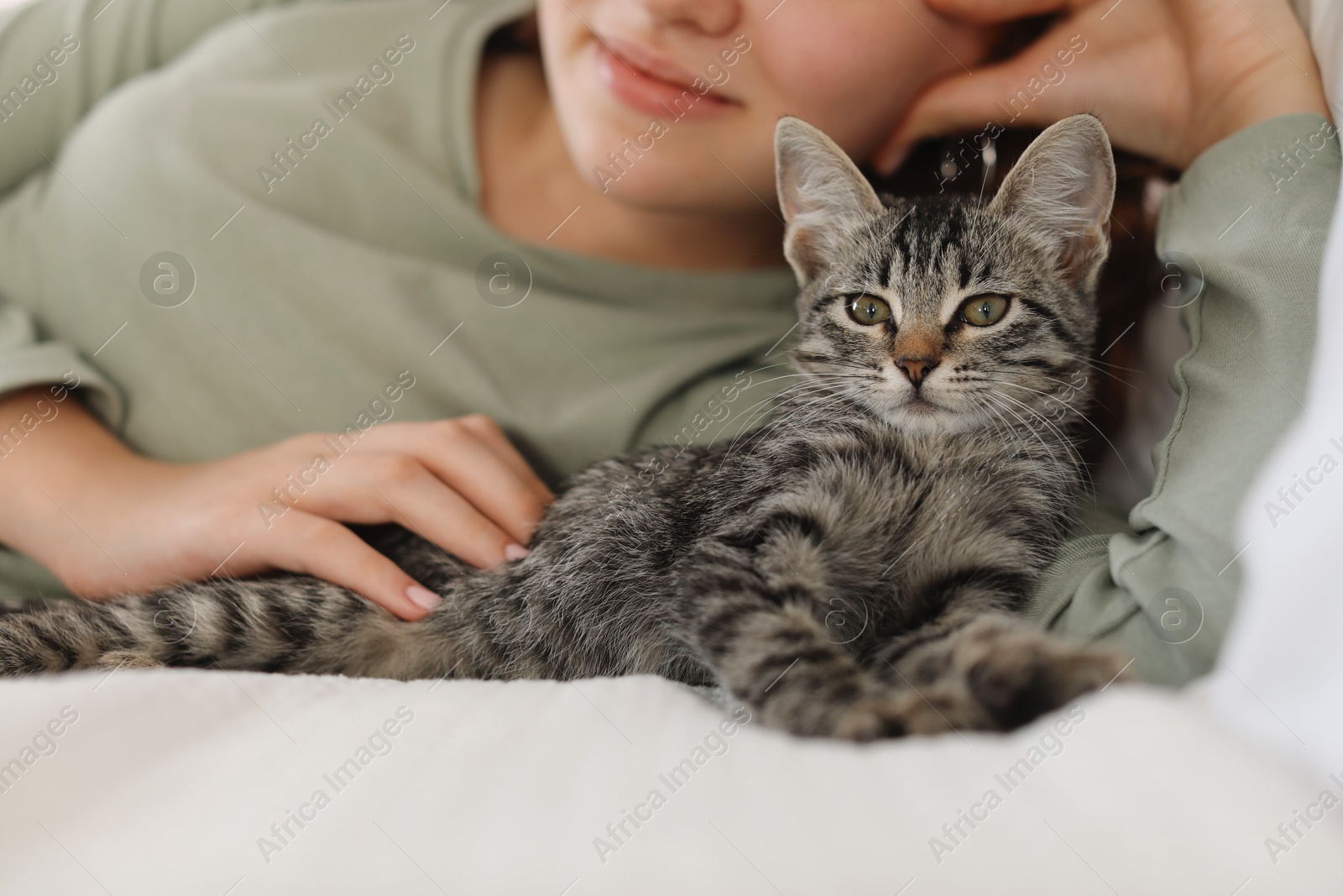 Photo of Teenage girl with cute cat on bed at home, closeup