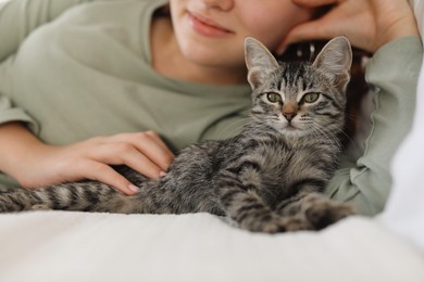 Photo of Teenage girl with cute cat on bed at home, closeup