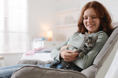 Photo of Beautiful teenage girl with cute cat on sofa at home