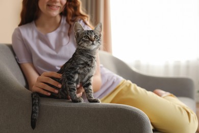 Teenage girl with cute cat on sofa at home, closeup