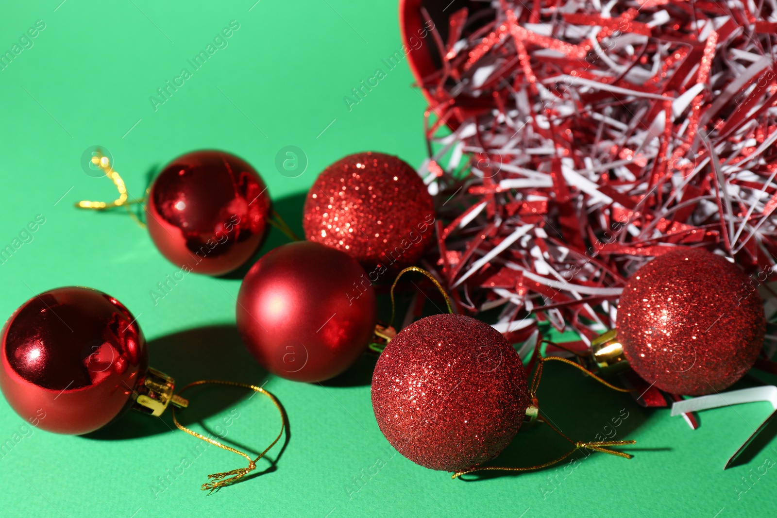 Photo of Red Christmas balls and shiny filler on green background, closeup