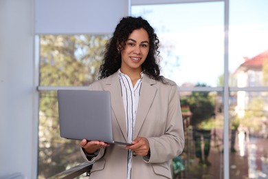 Photo of Portrait of young woman with laptop wearing stylish suit indoors